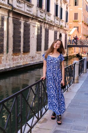 Young female tourist standing near banister in Venice, Italy. Concept of last minute tours to Europe and romantic venetsian street.の写真素材