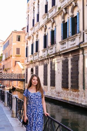 Young woman standing near banister in Venice, Italy. Concept of last minute tours to Europe and romantic venetsian street.の写真素材