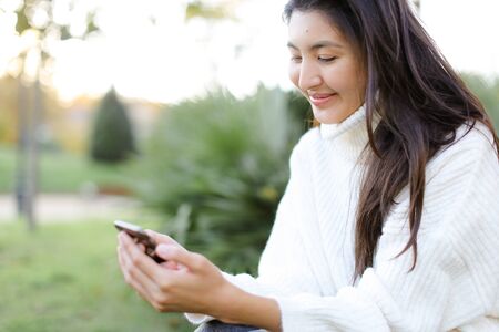 Focus on korean woman keeping smartphone and smiling. Concept of asian modern technology.の写真素材