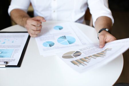 Male person working with documents and diagrams, wearing white shirt and watch.の写真素材