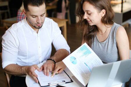 Young successful husband and wife working with documents at cafe. Concept of family business and partners.の写真素材