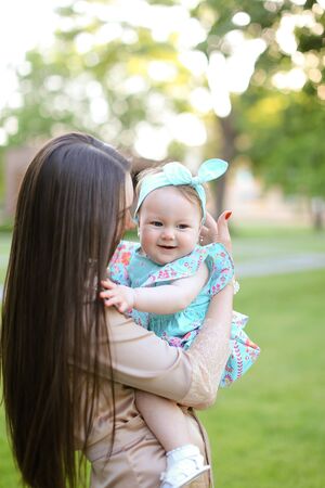 Young brunette woman holding little daughter in garden. Concept of motherhood and child.の写真素材