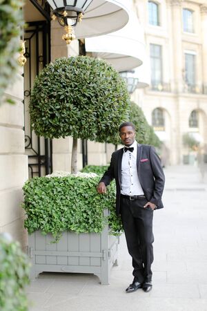 Afro americanmale person wearing suit and standing near tree in city. Concept of black businessman.の写真素材