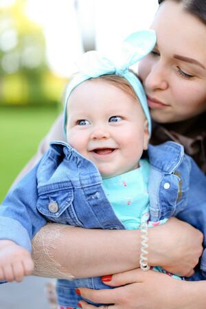 Closeup young european mother kissing little daughter wearing jeans jacket. Concept of motherhood and children.の写真素材