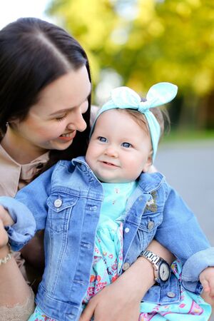Closeup young gladden mother kissing little daughter wearing jeans jacket. Concept of motherhood and children.の写真素材