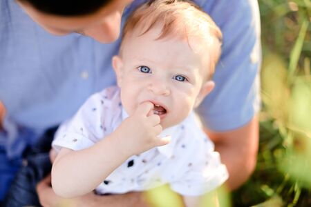 Closeup portrait of little male baby on father blue t shirt background. Concept of childhood.の写真素材