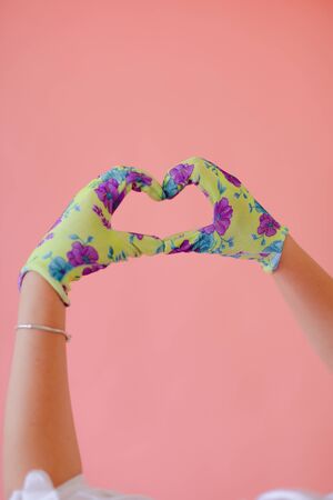 Closeup hands wearing gloves showing heart gesture by hands in pink monophonic background with copyspace. Concept of love and positive.の写真素材