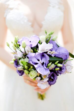 Closeup bridal bouquet of violet flowers. Concept of wedding photo session and floristic art.の写真素材