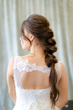Back view of caucasian brunette bride with braid hair at studio. Concepf of bridal hair do and wedding.の写真素材