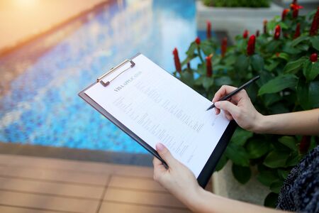 large portrait of woman's hand fills out visa application form for Iceland against pool background. concept of long-term travel to warm countries. Front used with Open Font Licenseの写真素材