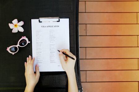 sunny flat lay of woman fill visa application for travel, sunlight portrait with sunglasses. and flower. concept of traveling journey agencies, tourist agency. Front used with Open Font Licenseの写真素材
