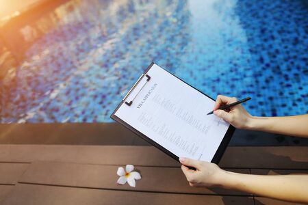 woman holds pen and visa application in UAE Dubai, contributes her data for new trip to foreign country. concept of signing papers, traveling to other countries. Front used with Open Font Licenseの写真素材