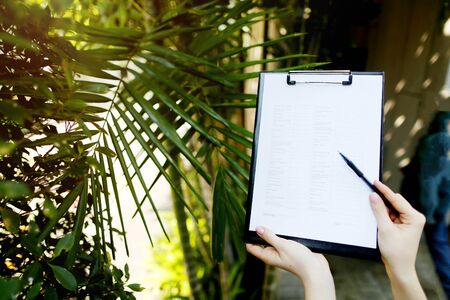 Beautiful hands of girl suggest signing an empty paper or contract on background of palms and sun. concept of working in warm countries, travel or remote work freelancing. Front used with Open Font Licenseの写真素材