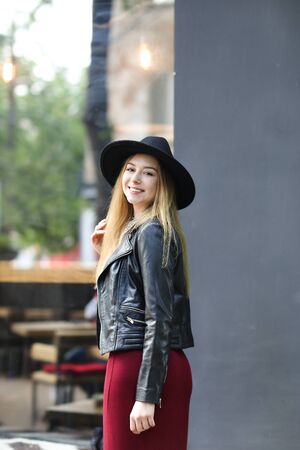 Young caucasian girl wearing black hat and red dress, and leather jacket.. Concept of fashion and european youth.の写真素材