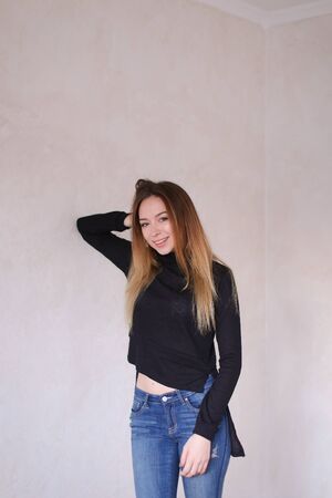 Young caucasian girl wearing black blouse and jeans standing in monophonic background. Concept of fashion and youth.の写真素材