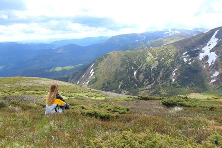Female tourist sitting and looking on Alps. Concept of tourism and soending summer vacations in mountains.の写真素材