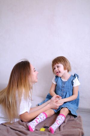 Young happy mother playing with little daughter and sitting on bed. Concept of children, motherhood and leisure.の写真素材
