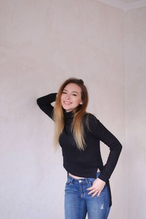 Young caucasian woman wearing black blouse and jeans standing in monophonic background. Concept of fashion and youth.の写真素材