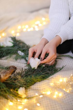 Female hands, green wreath and shimmering yellow garlands. Concept of handmade decorations for Christmas and winter holidays.の写真素材