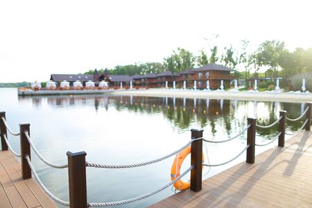 Empty lake with lifebuoy and houses in background. Concept of calm resort for summer vacations.の写真素材