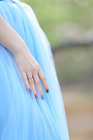 Female arm with ring and manicure on blue dress background. Concept of marriage person.の写真素材