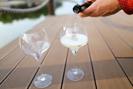 Male hands wearing red shirt pouring wine on wooden table. Concept of sommelier profession and alcohol.の写真素材