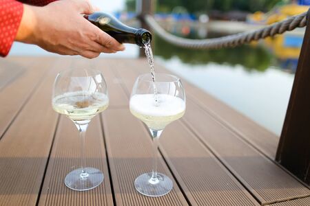 Man hands wearing red shirt pouring wine on wooden table. Concept of sommelier profession and alcohol.の写真素材