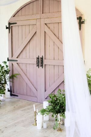 White candles near wooden gate and plants. Concept of wedding decorations.の写真素材