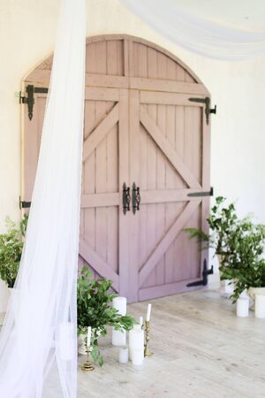 Two candles near wooden gate and plants. Concept of wedding decorations.の写真素材