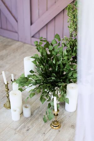 White candles near wooden door and plants. Concept of wedding decorations.の写真素材