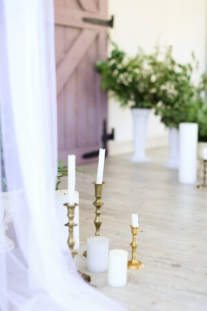 Two candles near wooden door and plants. Concept of wedding decorations.の写真素材