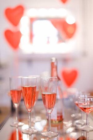 Chapagne wineglasses with pink wine and heart decorations in background. Concept of alcohol and valentine party.の写真素材