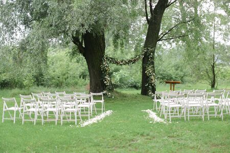 Tender flower arch for wedding and white chairs in park. Concept of place for ceremony and bridal decorations.の写真素材