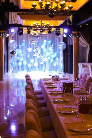 Served table with blue balloons on illuminated scene at restaurant. Concpt of cafe decorations.の写真素材
