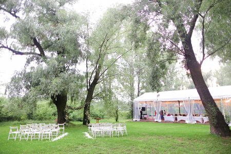 White wooden chairs and tender flower arh for wedding in park. Concept of bridal place for ceremony.の写真素材