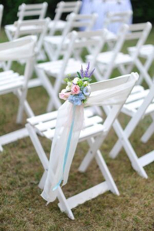 White chairs on green grass background. Concept of wedding seating places.の写真素材