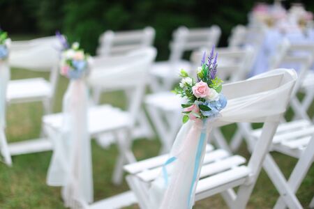 White chairs on green grass background, blurred photo. Concept of wedding seating places.の写真素材
