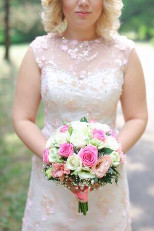Blonde bride keeping violet bouquet of flowers. Concept of wedding and floristic art.の写真素材
