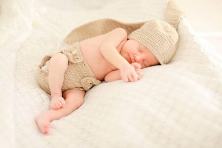 Little newborn baby sleeping and wearing crocheted clothes, white background. Concept of babies and new life.の写真素材