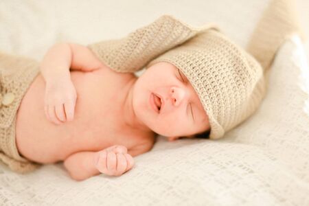 Nice newborn baby sleeping and wearing crocheted clothes, white background. Concept of babies and new life.の写真素材
