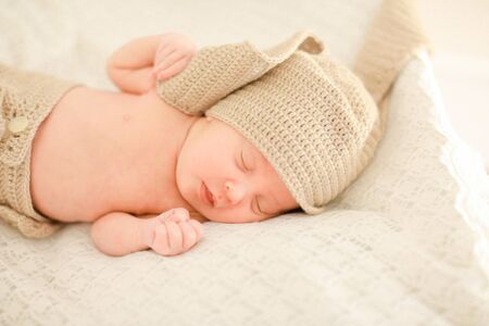 Nice caucasian newborn baby sleeping and wearing crocheted clothes, white background. Concept of babies and new life.の写真素材