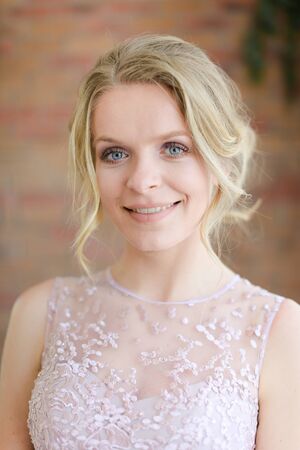 Closeup portrait of blonde bride with tender hairdo. Concept of gentle makeup for fiancee.の写真素材