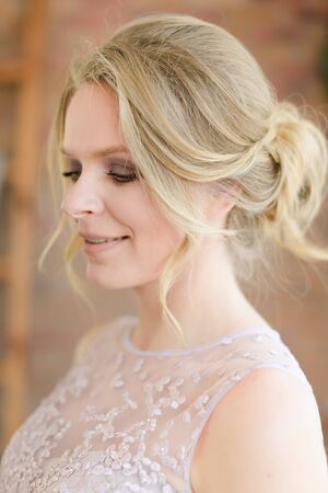 Closeup portrait of blonde beautiful bride with tender hairdo. Concept of gentle makeup for fiancee.の写真素材