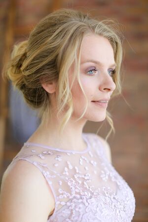 Closeup portrait of blonde charming bride with tender hairdo. Concept of gentle makeup for fiancee.の写真素材