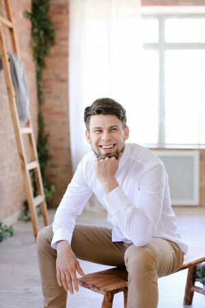 Young businessman sitting near brick wall and ladder. Concept of successful people and interior.の写真素材