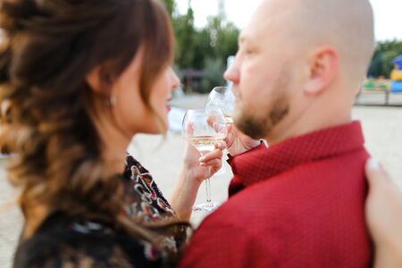 Bald husband wearing red shirt dancing with wife and drinking wine. Concept of leisure time, romantic love and weekends.の写真素材
