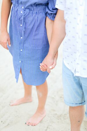 Closeup holding hands of caucasian couple walking barefoot on sand. Concept of summer vacations and relationships.の写真素材