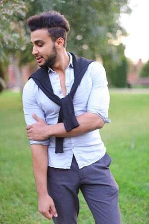 Young handsome hispanic male person walking in park. Concept of stylish youth and foreign students.の写真素材