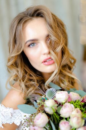 Close up portrait of young beautiful caucasian bride with bouquet at studio. Concept of bridal photo session and floristic art.の写真素材