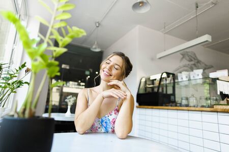Young happy woman sitting at cafe and having break. Concept of taking rest and beautiful female person.の写真素材